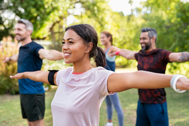 mixed-race-woman-exercising-in-park-with-mature-friends-gm