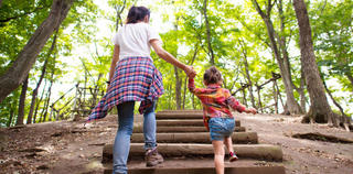 Mother and daughter climbing log steps in the woods.
