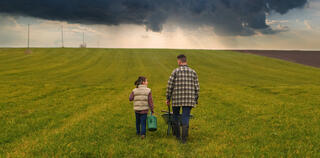 father and daughter walk through a field towards a storm on the horizon, symbolising the impending recession