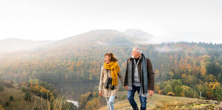 senior couple out walking wearing warm clothing awaiting winter