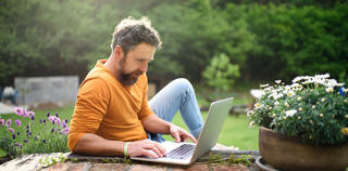 young man reading his laptop outside