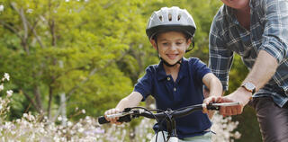 Grandfather teaching grandson to ride bicycle