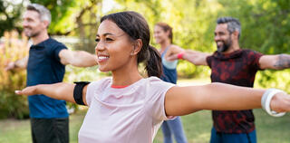 mixed-race-woman-exercising-in-park-with-mature-friends-gm