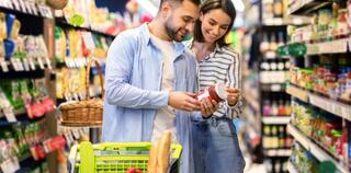 Smiling couple with the cart choosing products in supermarket