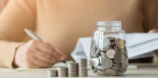 Woman with coins jar taking note to checklist expenses