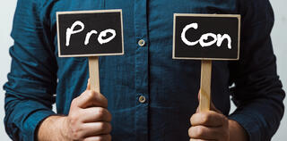 Man holding two chalkboards with Pro and con