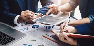 Financial advisors working for the company using tablet and computer technology in analysis.