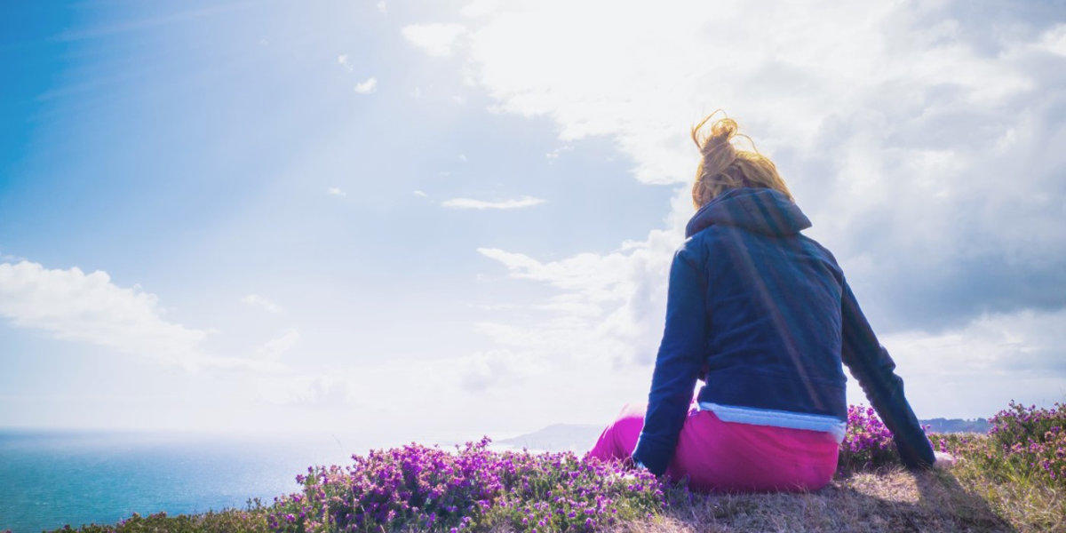 Girl sitting on a cliff overlooking the sea.