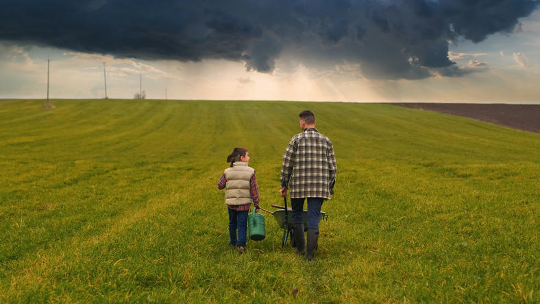 father and daughter walk through a field towards a storm on the horizon, symbolising the impending recession