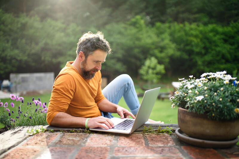 young man reading his laptop outside