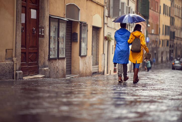 Back view of couple on rainy day while walking on the street