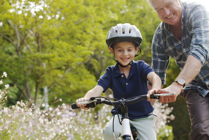 Grandfather teaching grandson to ride bicycle
