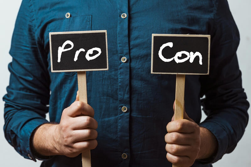 Man holding two chalkboards with Pro and con